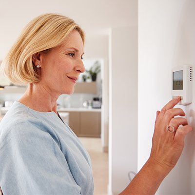 Woman adjusting thermostat