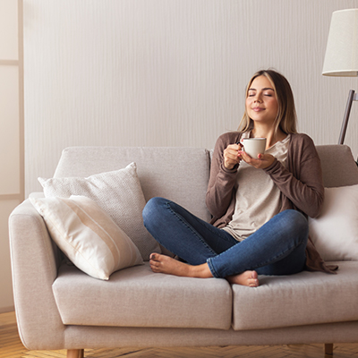 A woman sipping tea on her couch after receiving residential HVAC services from our HVAC contractor in London, Ontario