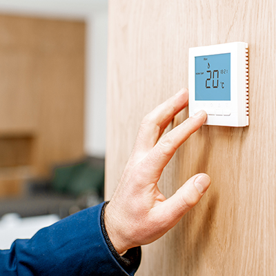 A hand adjusting a thermostat after a visit from our London HVAC contractor