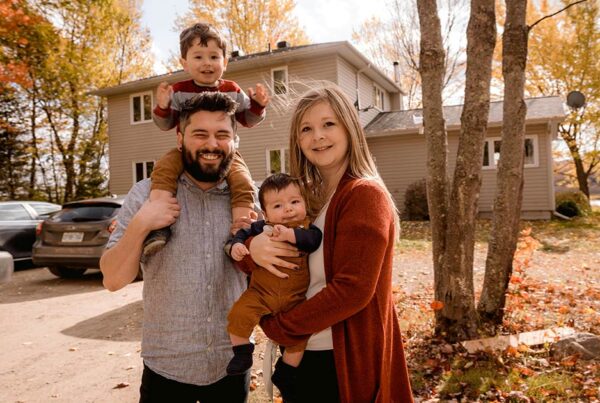 A family standing outside of their home in fall about to complete their fall home maintenance checklist
