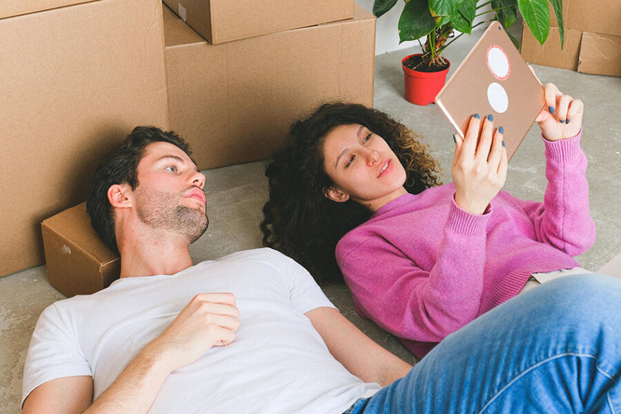 New homeowners lying next to packing boxes discussing HVAC mistakes