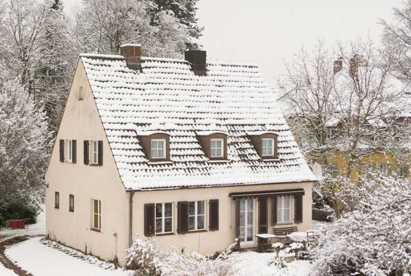 A house with a snow covered roof for a blog post about how often to change your furnace filter